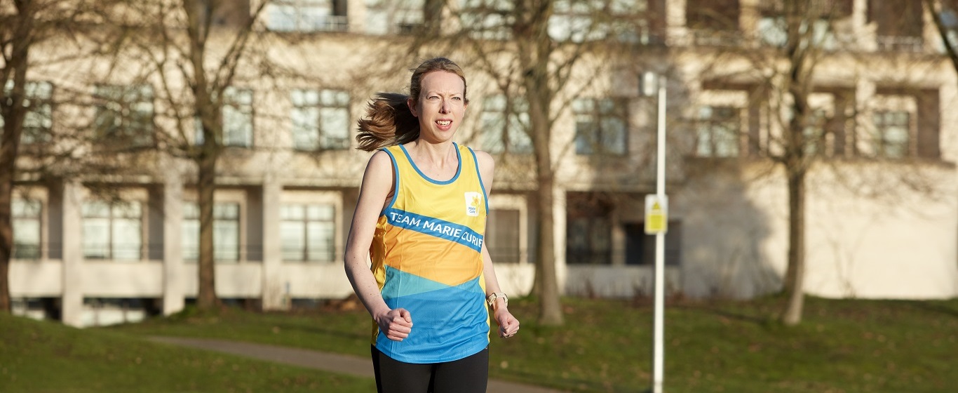 Female member of staff team running in Marie Curie vest